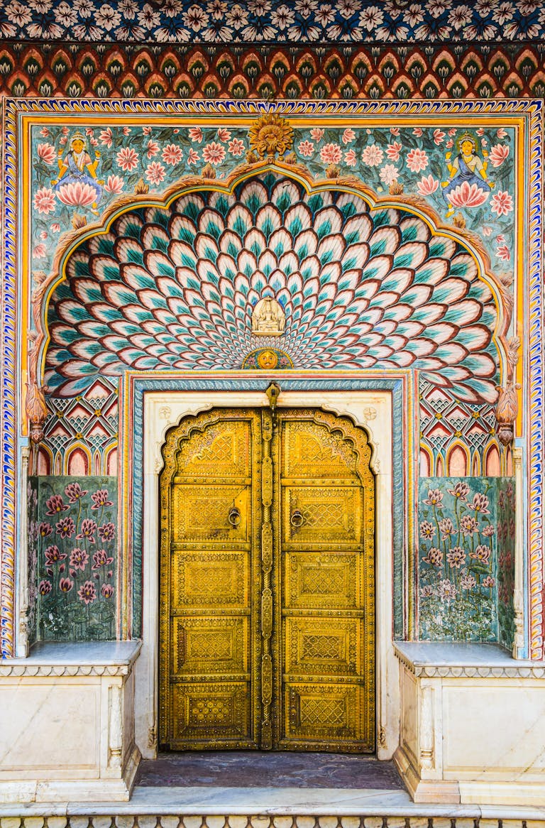 Intricate Mughal architecture at Jaipur's City Palace, showcasing vibrant peacock patterns and gold detailing.