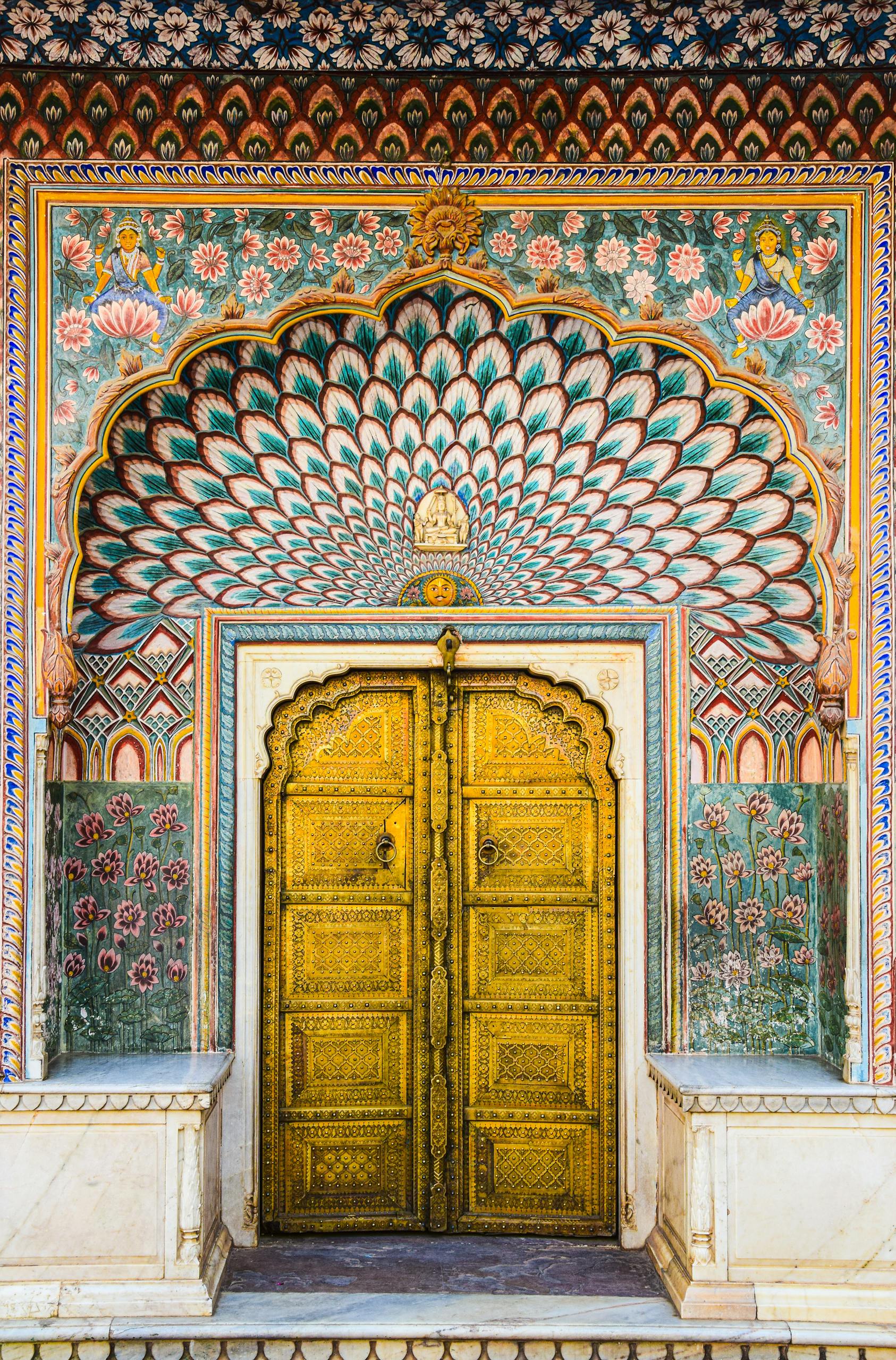 Intricate Mughal architecture at Jaipur's City Palace, showcasing vibrant peacock patterns and gold detailing.